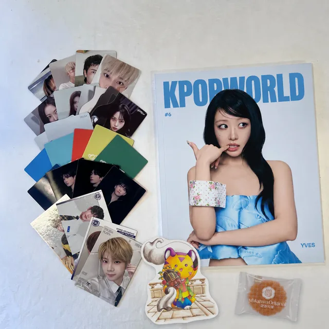 Photocards fanned out next to KPOPWORLD magazine #6, an original art piece and a wrapped yakgwa cookie